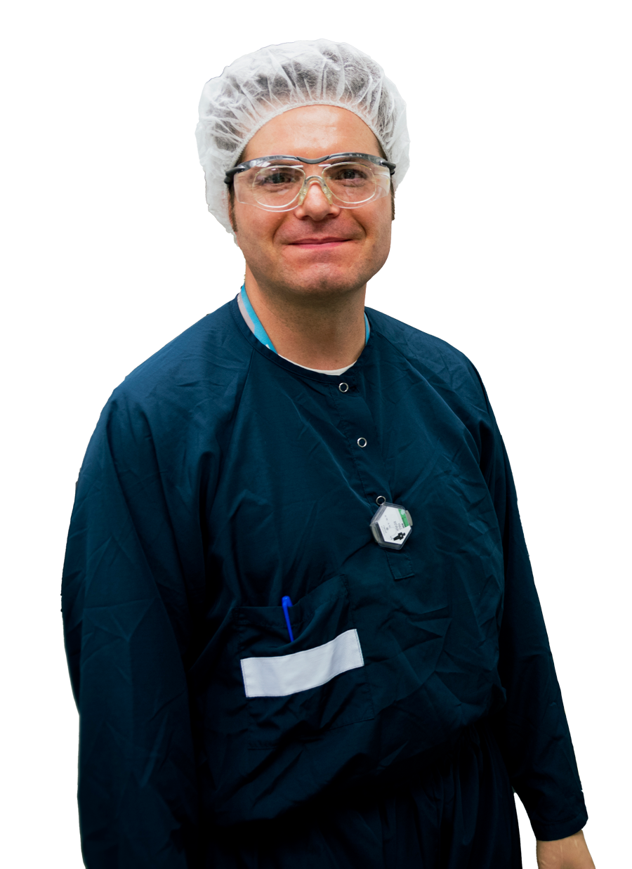 Male lab technician in blue uniform smiles at camera.
